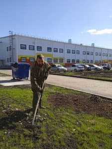 Сотрудник разравнивает землю граблями во время субботника